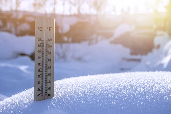 Wooden thermometer on white snow background