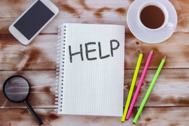 Bir fincan kahve ve bir akıllı telefon ile ahşap bir masa üzerinde bir defter yardım kelime