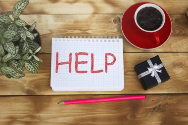 Bir fincan kahve ve bir hediye kutusu ile ahşap bir masaya yatıyor bir defter yazıt yardım