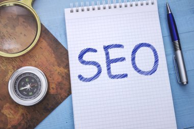 Bir not defteri Seo metin ile ahşap bir masaya seyahat aksesuarları ile yatıyor.