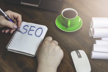 Beyaz Notepad Seo yazıt ile bir tanıtıcı ve bir fincan kahve ile ahşap bir masaya yatıyor