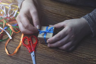 Kadın mavi bir yay bir hediye kutusu bağlar.