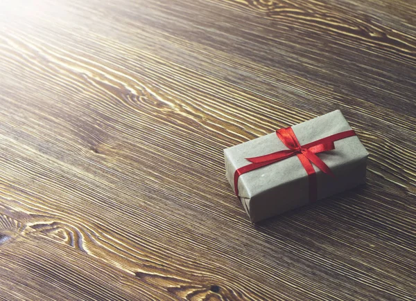 木桌上有一个带红色丝带的礼品盒 — 图库照片