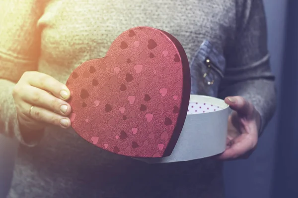 A woman opens a box in the form of a heart