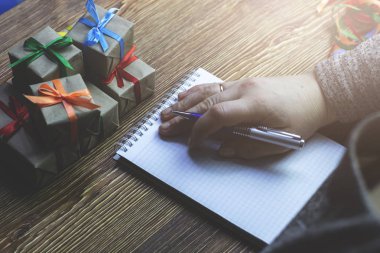 Hediyeler yanında ahşap bir masada oturan yatıyor defter, elini koyarak kadın