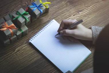 Ahşap bir masa üzerinde üstten görünüm yatıyor bir defter bir not bir kadın yapar