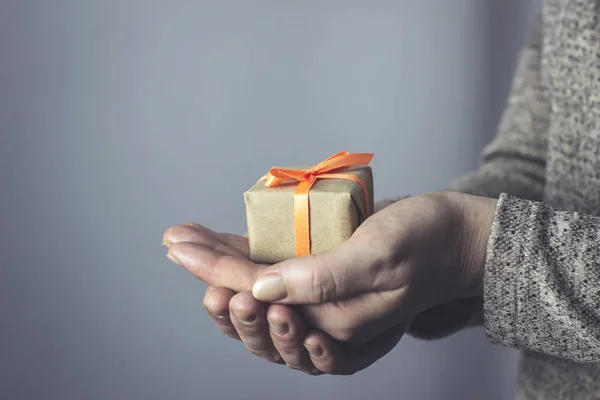 Woman holding a gift box with an orange ribbon