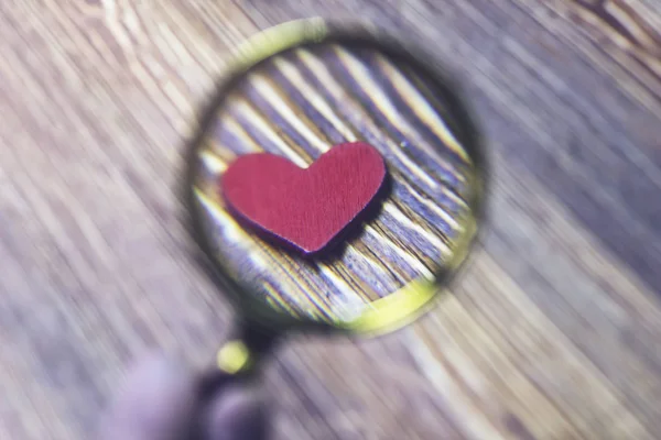 Little red heart magnified by a magnifying glass, close-up