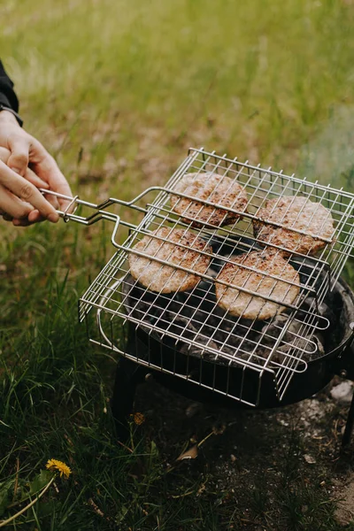 El proceso de preparación de chuletas de carne para hamburguesas a la parrilla. Picnic al aire libre — Foto de Stock