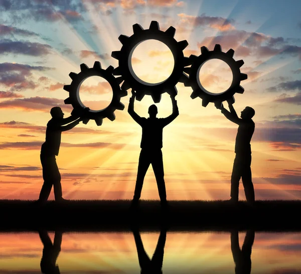 Silhouette of the three men holding the gears put them together in one gear. The concept of mutual aid