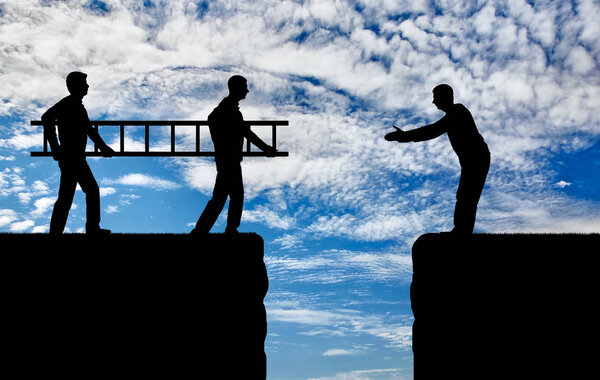 Silhouette two men carry a ladder to pave the way across the abyss for another man. The concept of teamwork