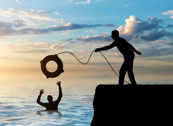 A silhouette of a man throws a lifeline to another man who is drowning in the water. The concept of mutual assistance in a business team