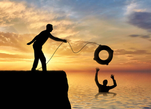 A silhouette of a man throws a lifeline to another man who is drowning in the water. The concept of mutual aid