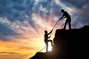 Siluet dağcı başka bir tırmanıcı, onu bir halat atma tepesine tırmanmak için yardımcı olur. Kavramsal yardım sahne