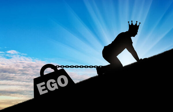 The silhouette of an egotistic man with a crown on his head creeps up. To his feet is bound the load - the ego. Conceptual scene of selfishness