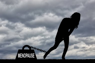 Bir kadın silueti ve menopoz ağır bir yük bacağı için zincirli. Menopoz kadınlarda kavramsal görüntü