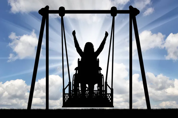 Silhouette einer glücklichen Frau ist eine behinderte Person im Rollstuhl auf einer adaptiven Schaukel für behinderte Menschen — Stockfoto