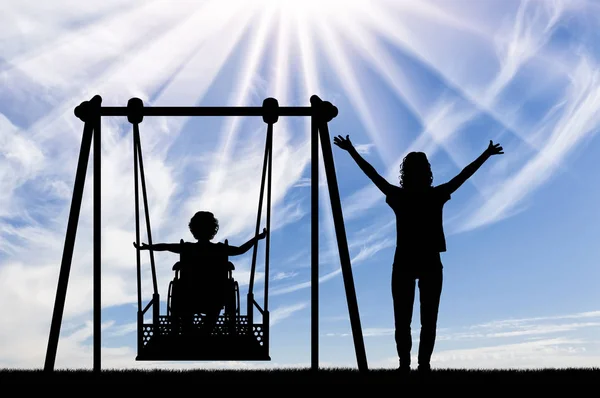 Happy Child is uitgeschakeld in een rolstoel op een adaptieve schommel voor gehandicapte kinderen met moeder — Stockfoto