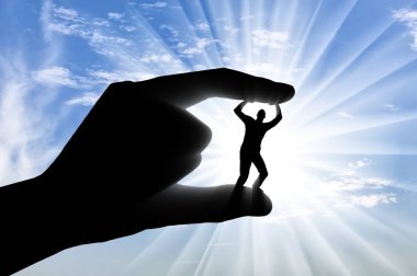 Zorbalık konsepti. Bir elin silueti bir adamın parmaklarının arasında.