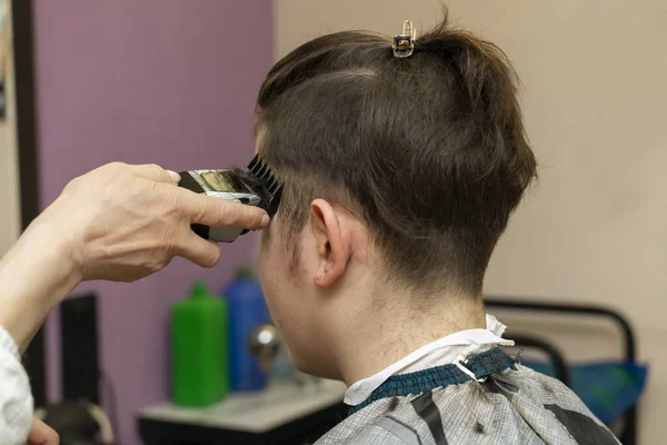 a teenager cut a hair clipper in a hairdresser