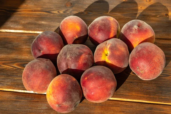set of ripe juicy peaches on wooden background in sunny harsh light