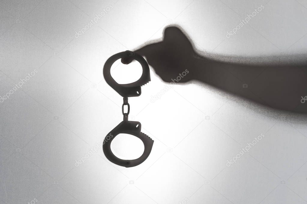 Handcuff ready for criminals. Arrest concept. Silhouette of sheriff's hand hold handcuff