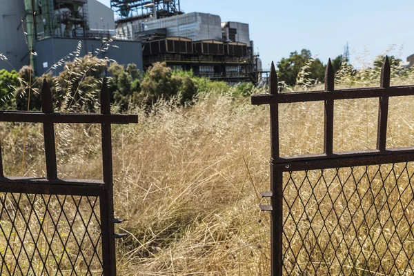 Rusted and pointed metal fence surrounding an abandoned oil refinery in Gela, Sicily, Italy