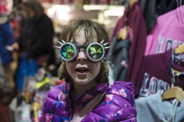 Little girl with a Gothic sunglasses with diffracted lens or Kaleidoscope in a fashion shop of Camden Lock Market or Camden Town in London, England, United Kingdom clipart