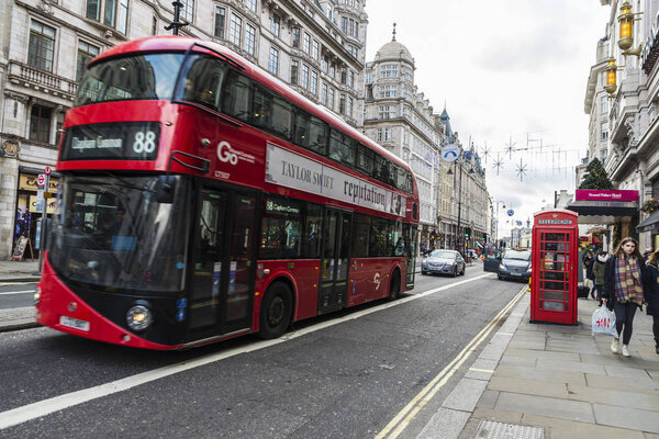 London, United Kingdom - January 1, 2018: Red double-deckers bus circulating with people around and a telephone box in London, United Kingdom