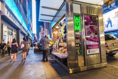 New York City, USA - July 30, 2018: Newsstand at night on Seventh Avenue (7th Avenue) next to Times Square with people around in Manhattan in New York City, USA clipart