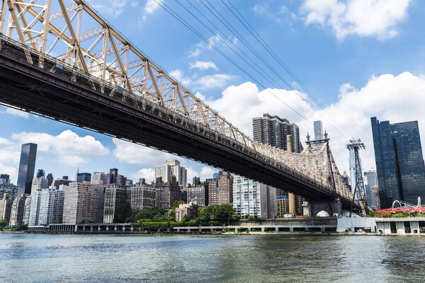 Low angle view of the Ed Koch Queensboro Bridge, also known as the 59th Street Bridge, seen from Roosevelt Island with the Manhattan skyline in New York City, USA