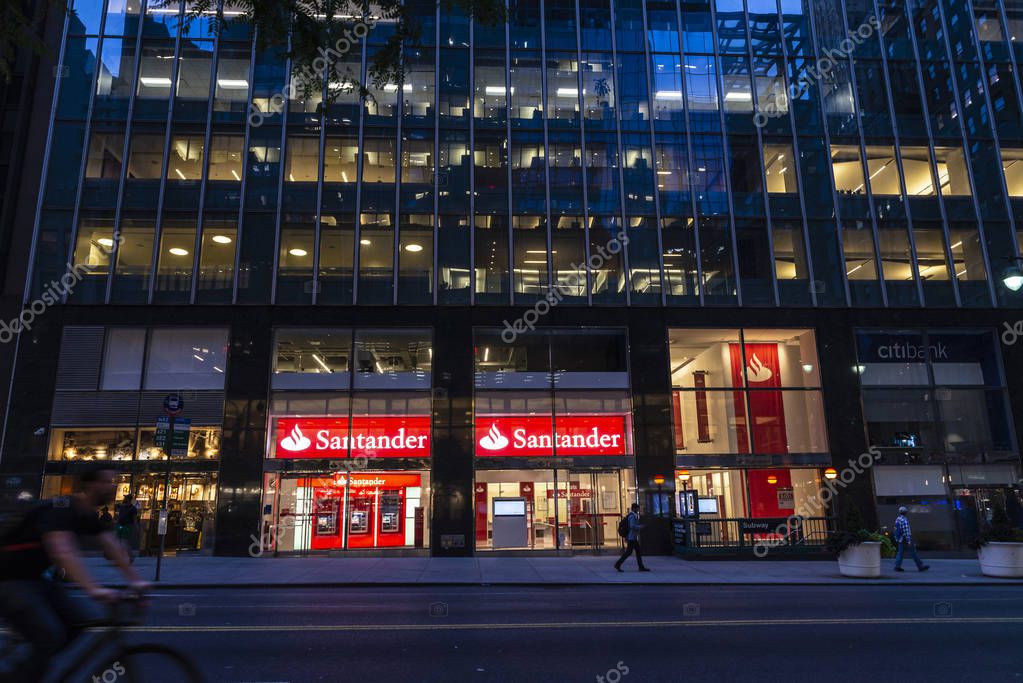New York City, USA - August 1, 2018: Facade of a bank branch of Santander Bank at night with people around in Manhattan, New York City, USA