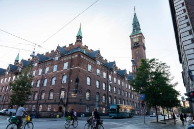 Kopenhag, Danimarka - 26 Ağustos 2019: Kopenhag, Danimarka 'da belediye binasının arka planında bisikletli insanlarla yürüme