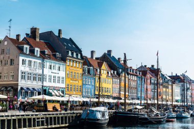 Kopenhag, Danimarka - 27 Ağustos 2019: Teras barında içki içen insanlar ve Nyhavn, Kopenhag, Danimarka 'da bir kanalda demirlemiş eski ahşap yelkenliler 