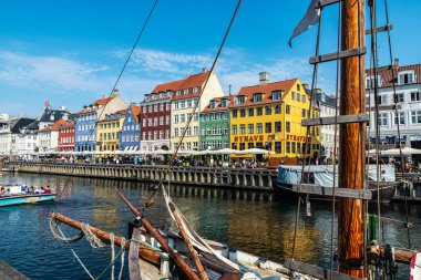 Kopenhag, Danimarka - 27 Ağustos 2019: Teras barında içki içen insanlar ve Nyhavn, Kopenhag, Danimarka 'da bir kanalda demirlemiş eski ahşap yelkenliler 