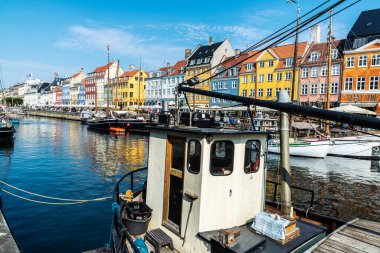 Kopenhag, Danimarka - 27 Ağustos 2019: Teras barında içki içen insanlar ve Nyhavn, Kopenhag, Danimarka 'da bir kanalda demirlemiş eski ahşap yelkenliler 