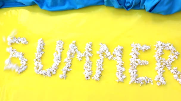 The inscription Summer is written in white flowers of lilac on a yellow background. The word Summer is written with lilac flowers. Flower inscription Summer. — Stock Video