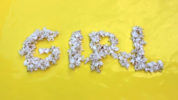 Inskriptionen Flicka är skriven i vita blommor av syren på en gul bakgrund. Ordet flicka är skrivet med lila blommor. Blomsterinskription Honung. — Stockvideo