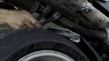 Adam motosikletin arka kanadına bant yapıştırıyor.