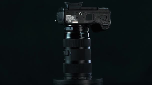 TOMSK, Ρωσία - 28 Μαΐου 2020: Panasonic Lumix DMC-GH5 κάμερα με Metabones speedbooster 0.71 ultra και sigma 18-35 1.8 τέχνη στέκεται σε ένα μαύρο πικάπ, Micro Four Thirds System, μαύρο φόντο — Αρχείο Βίντεο