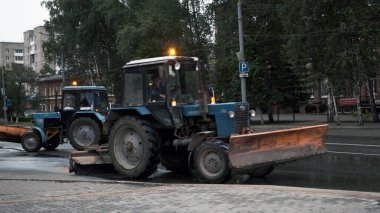 TOMSK, RUSSIA - 2 Haziran 2020: traktörler caddede sürüp asfaltı temizliyor