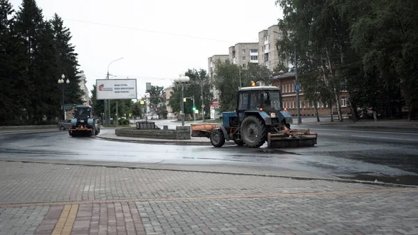 TOMSK,ロシア- 2020年6月2日:トラクターが通りをドライブし、アスファルトをきれいに — ストック写真