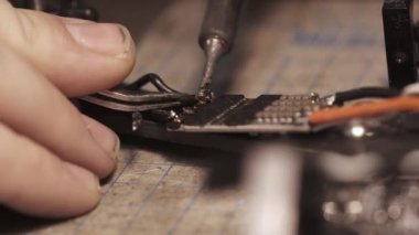 Kirli tırnaklı İHA kablolarını lehimleyen adam.