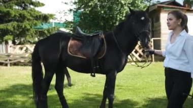 Beyaz gömlekli ve siyah pantolonlu bir kız ereksiyon olmuş bir ata liderlik ediyor.