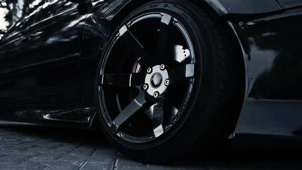 Вид збоку на чорний спортивний автомобіль і стильне колесо — стокове фото