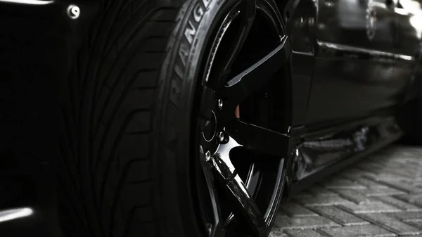 Vista lateral de um carro esporte preto e uma roda elegante — Fotografia de Stock