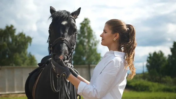 Dívka v bílé košili krmí koně z jejích rukou na ulici v teplém slunečném počasí — Stock fotografie