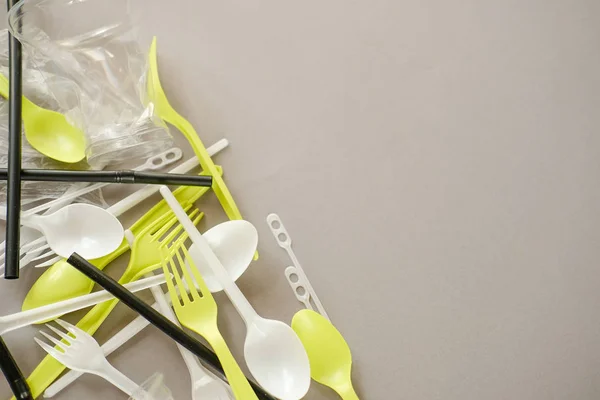 Plastik beyaz kaşıklar ve yeşil çatallar. gri arka plan. Ekoloji kavramı. kağıt alternatif olarak
