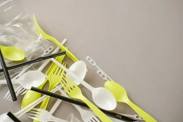 Plastik beyaz kaşıklar ve yeşil çatallar. gri arka plan. Ekoloji kavramı. kağıt alternatif olarak