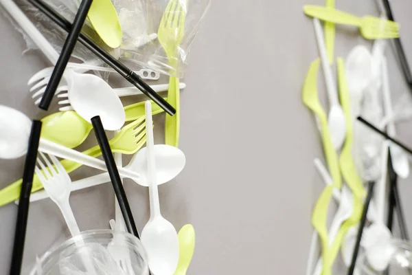 Plastik beyaz kaşıklar ve yeşil çatallar. gri arka plan. Ekoloji kavramı. kağıt alternatif olarak